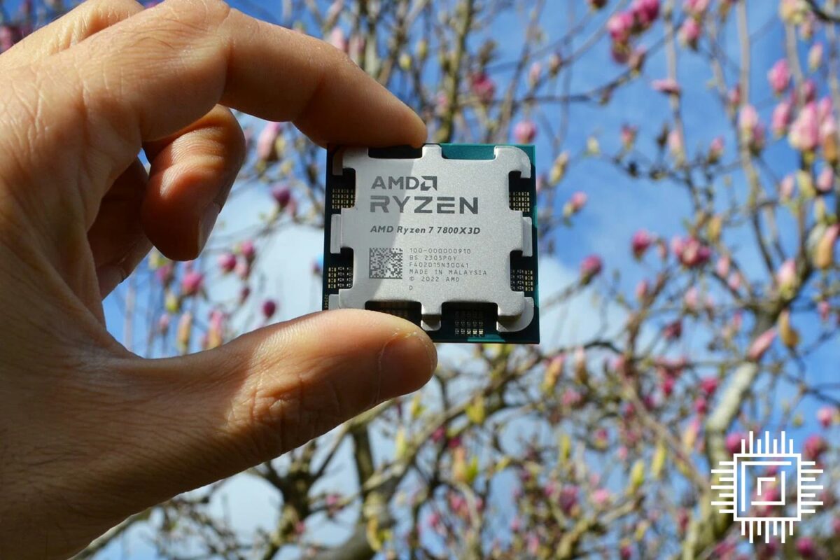The AMD Ryzen 7 7800X3D processor held up with trees in the background.