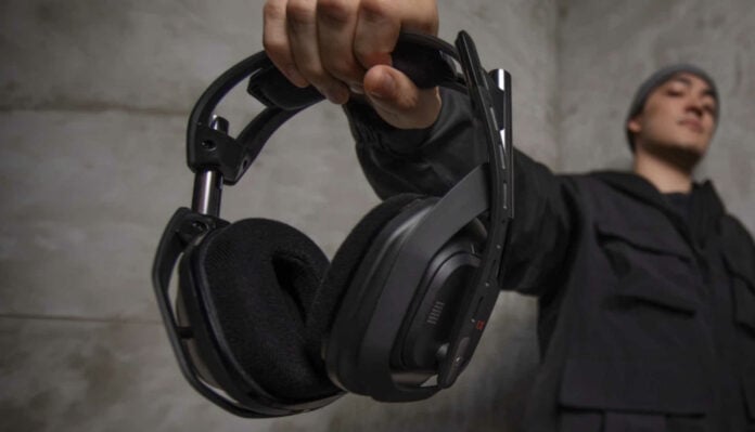 Logitech G ASTRO A50 X wireless gaming headset held by a person in black clothes.