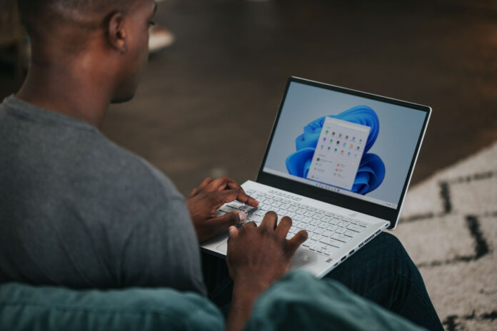 Person working on Windows 11 Laptop on the couch.