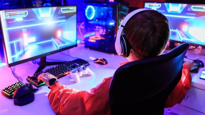 A gamer using a high-spec computer and monitor. He can save money by switching to a cheaper electricity tariff.