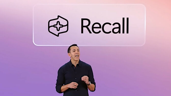 A Microsoft employee stands in front of a screen displaying the Windows Recall logo above their head