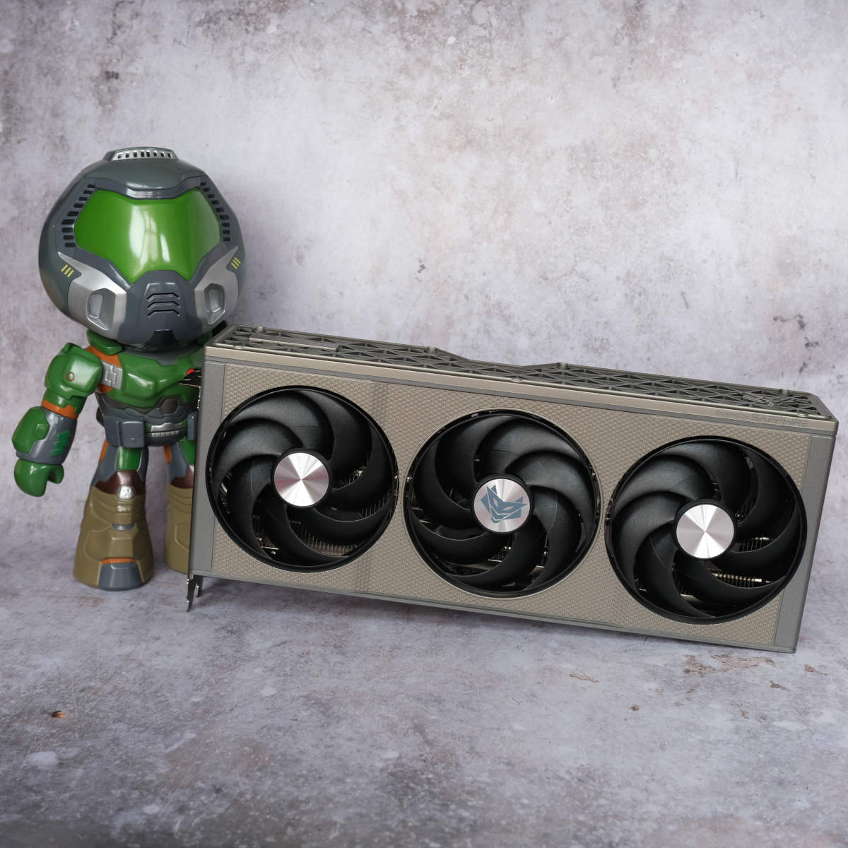 Doomguy figurine (left) standing next to Sapphire Nitro+ Radeon RX 9060 XT 16GB.