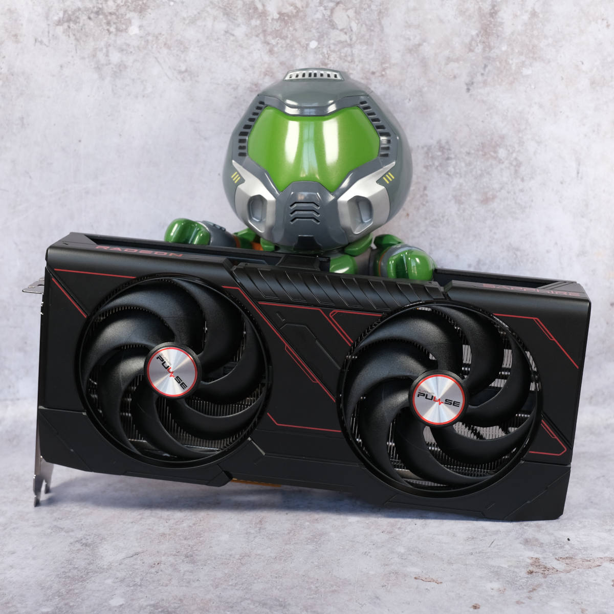 Doomguy collectible figure stands behind Sapphire Pulse Radeon RX 9070 graphics card.