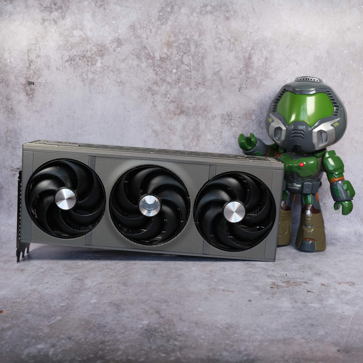 Doomguy collectible figure stands to the right of Sapphire Nitro+ Radeon RX 9070 XT graphics card.