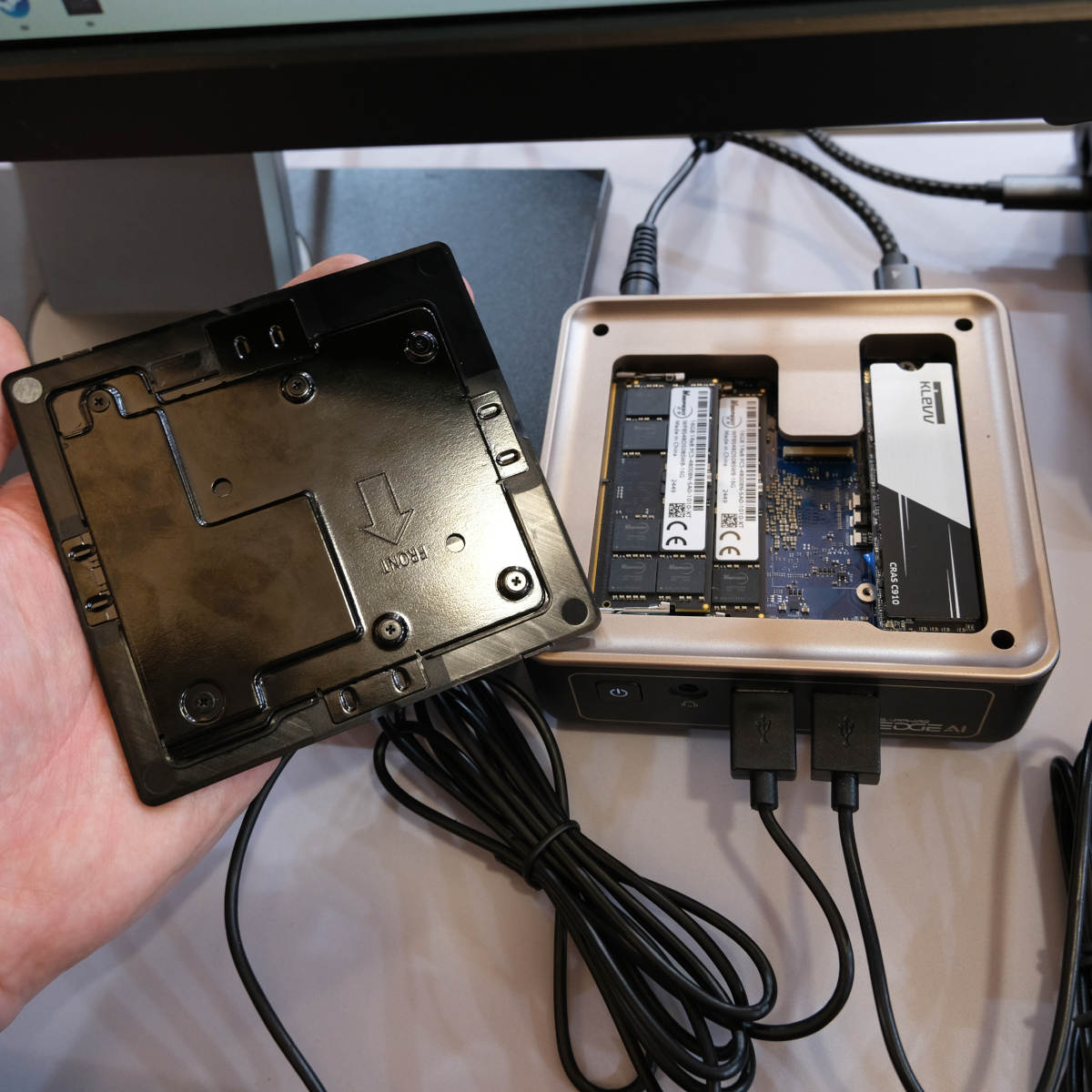 Top-down view of Sapphire Edge AI PC with its top plate removed, held in a hand on the left.