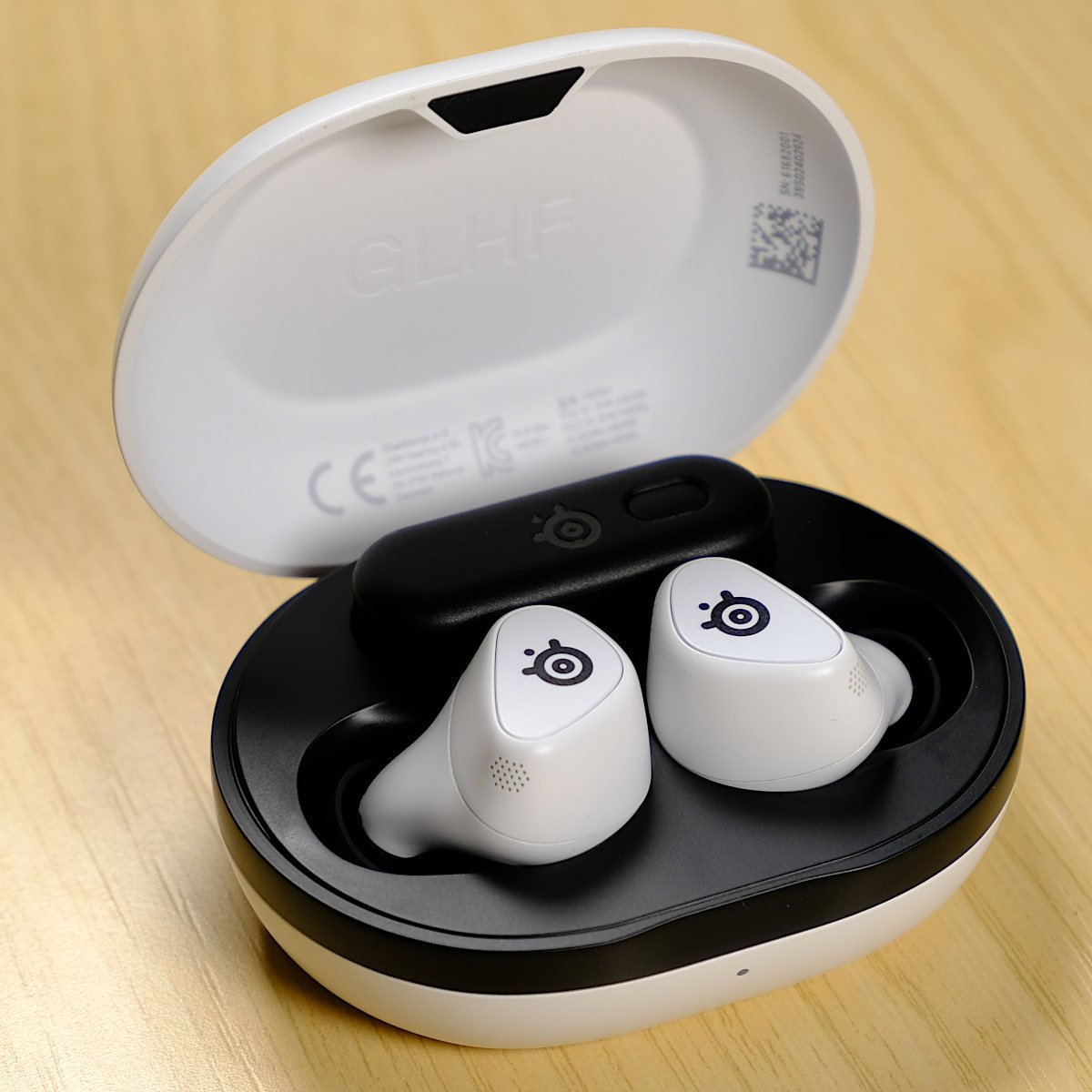 SteelSeries Arctis GameBuds, sat in their case, alongside their 2.4GHz dongle.