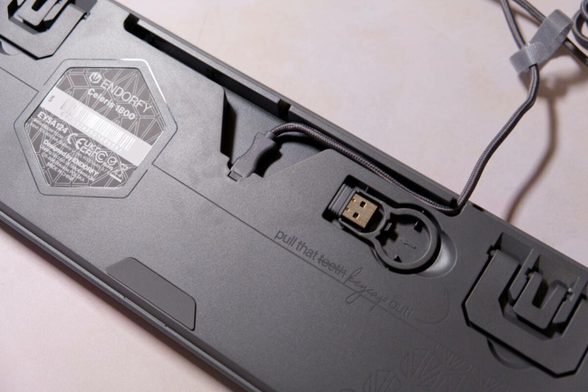 Underside of Celeris 1800 gaming keyboard, showing the docked USB receiver and cable routing.