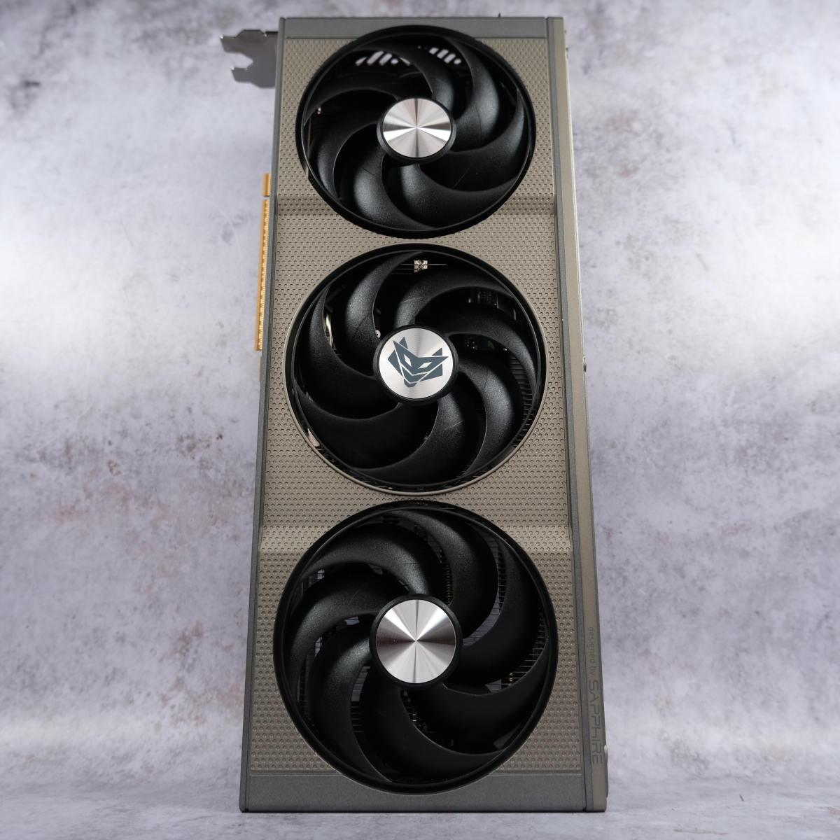 Sapphire Nitro+ Radeon RX 9060 XT 16GB stands vertically against a pearlescent backdrop.