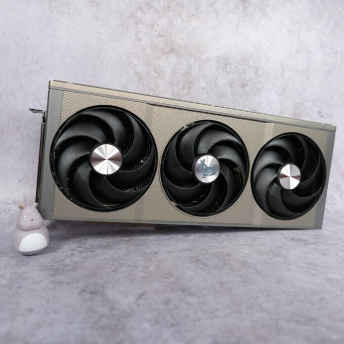 Sapphire Nitro+ Radeon RX 9060 XT 16GB sits vertically against a pearlescent background with a small mouse figurine (left) standing next to it.