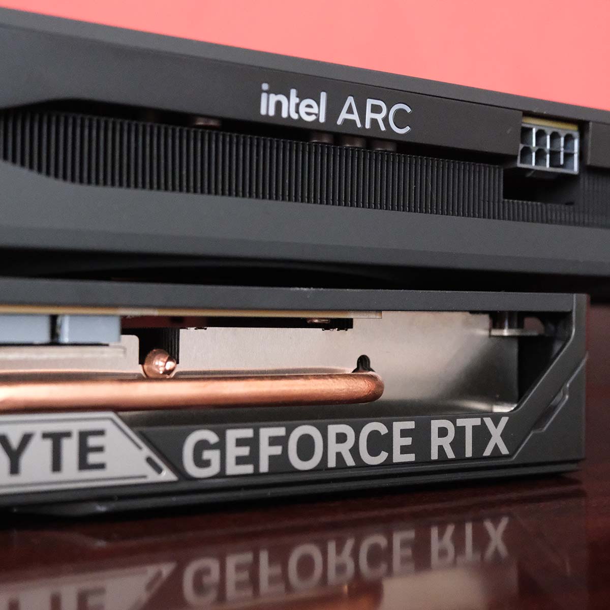 Intel Arc B580 sat atop Nvidia GeForce RTX 5080, zoomed in on their logos.