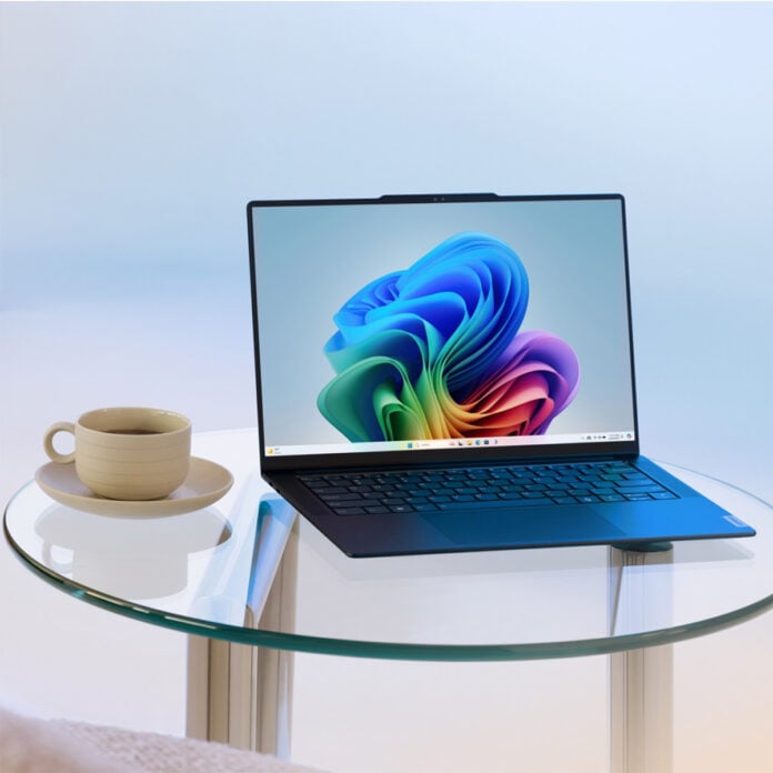 Windows 11 laptop sitting atop a glass table, with a cup of coffee (left) next to it.
