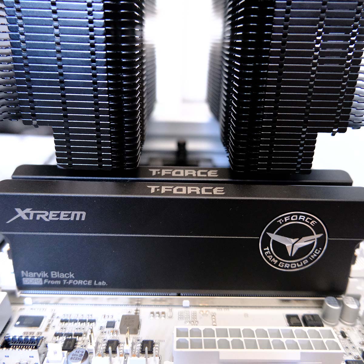 Two T-Force Xtreem CKD DDR5 RAM sticks, placed inside a motherboard, with a CPU cooler looming over uncomfortably close to both.