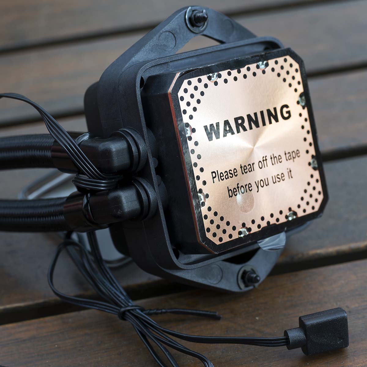 A close-up of be quiet! Pure Loop 3 LX 360's pump underside, a warning tape is attached to the coldplate.