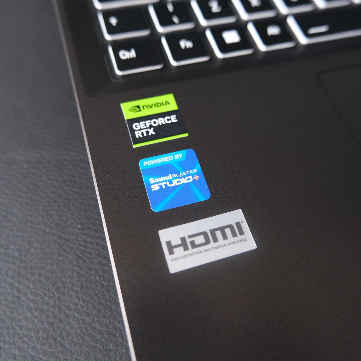 A close up of stickers on PCSpecialist Defiant 16, including Nvidia GeForce RTX (top), SoundBlaster Studio (middle), and HDMI (bottom).