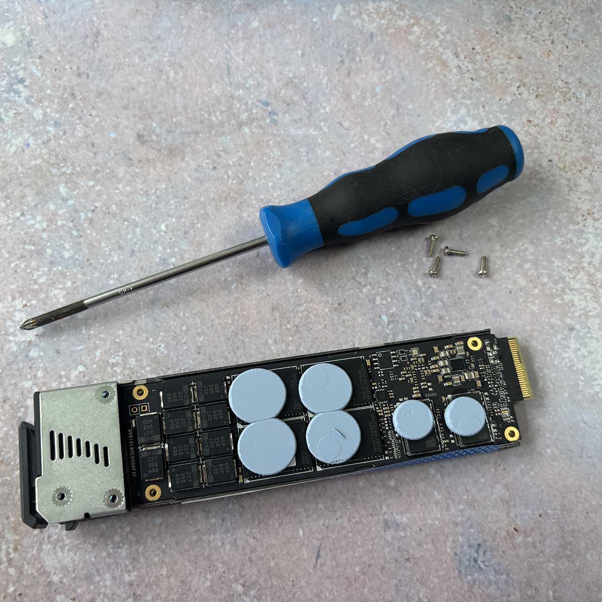 A picture of the QNAP E1.S SSD with the heatsink prised open.