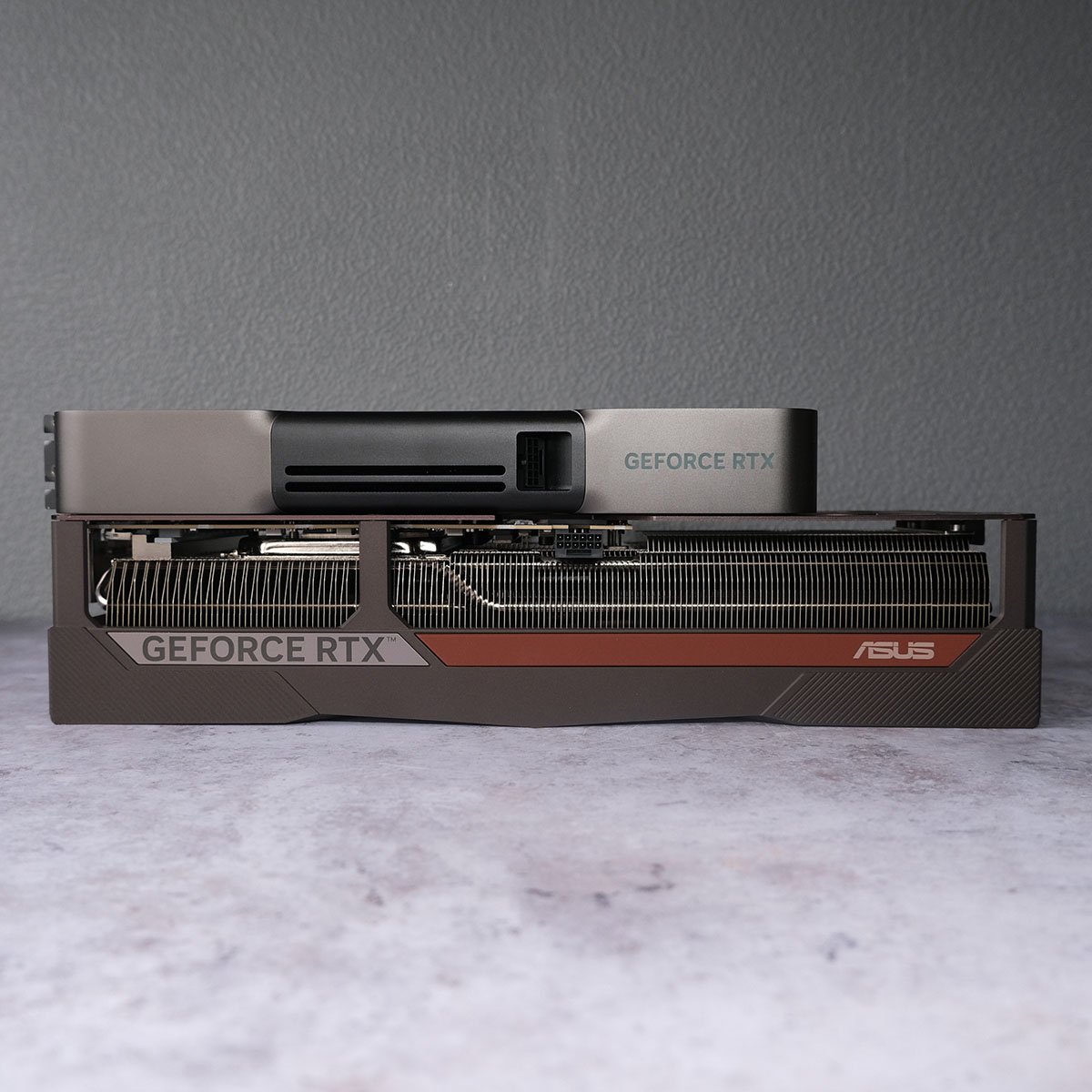 Nvidia GeForce RTX 5090 Founder Edition (top) and Asus GeForce RTX 5080 Noctua OC Edition (bottom) resting horizontally on top of one another.