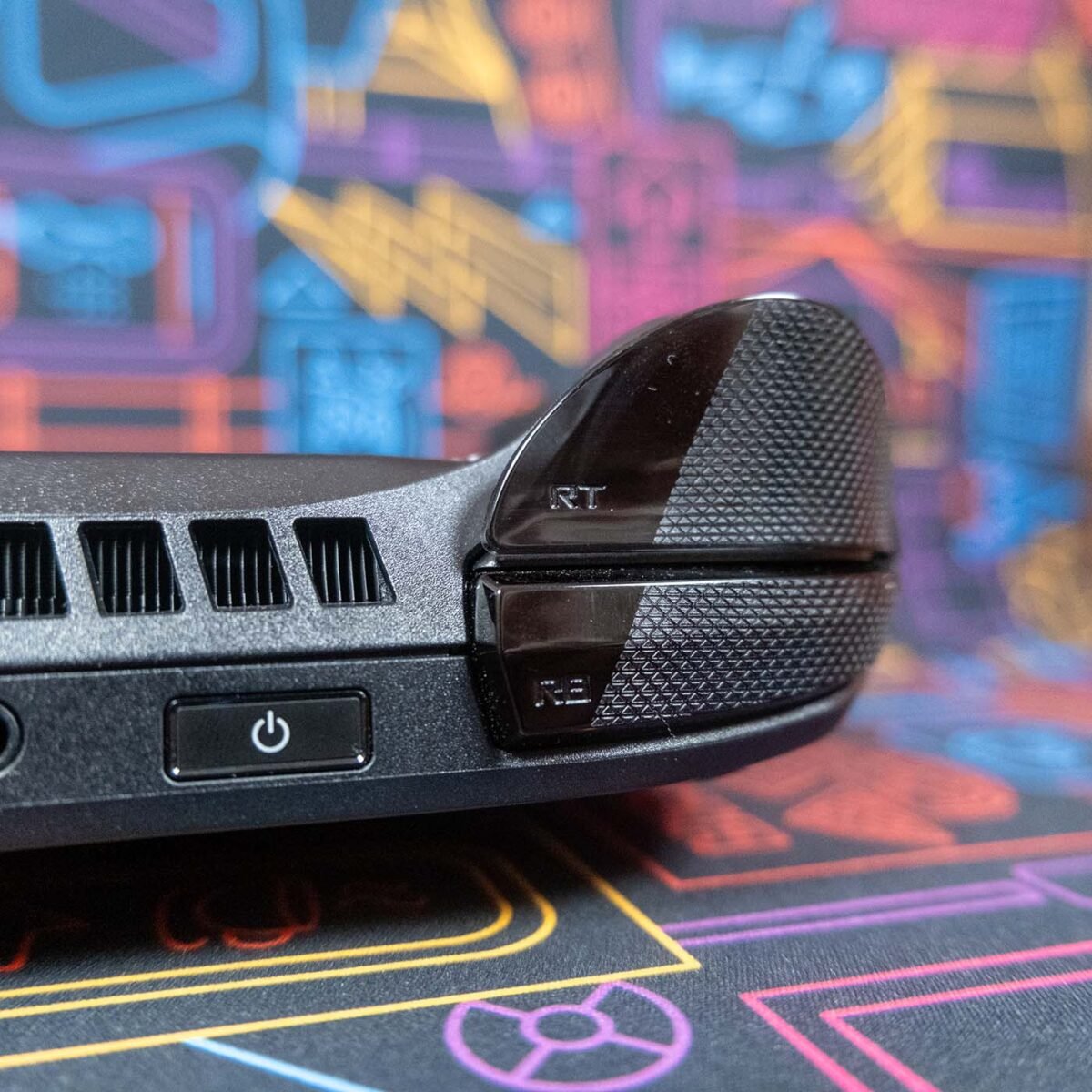 Close-up of triggers on ROG Xbox Ally X against a neon-style backdrop.