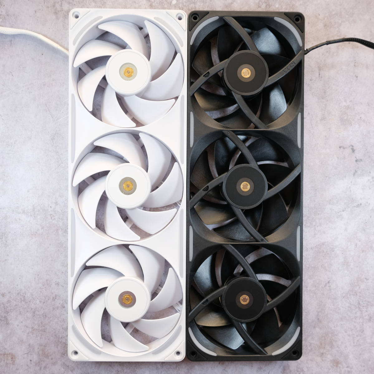 An NZXT F360X White (left) and Black (right) lying on their backs against a porcelain backdrop.