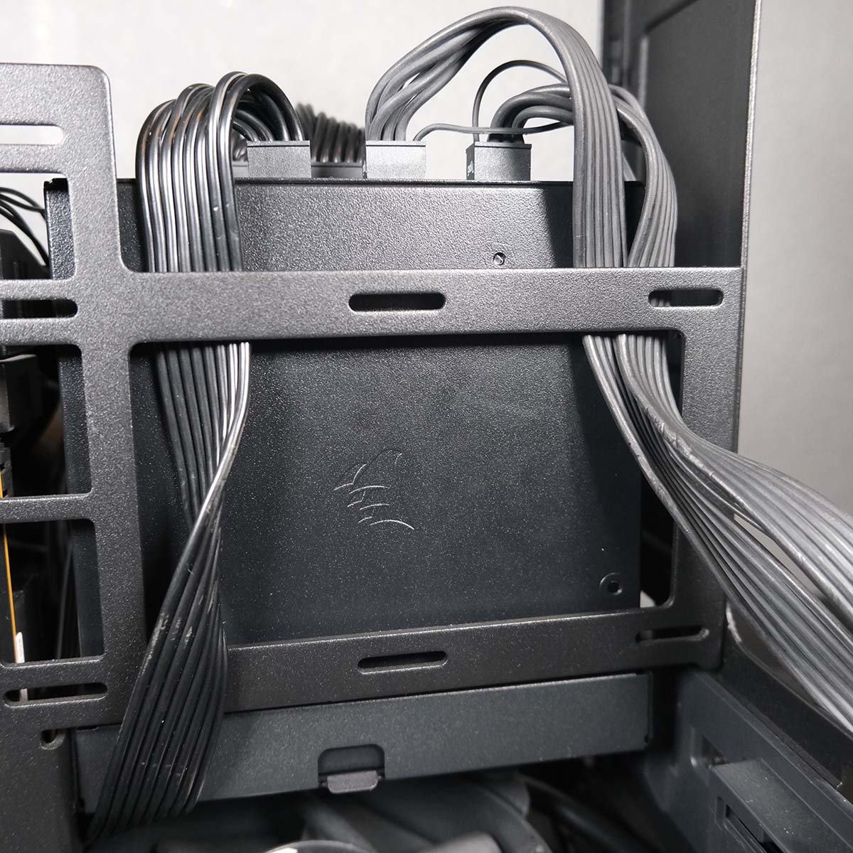 Modular cables flowing from Corsair SF1000L, routed through a cut-out in the spine of Fractal Design Era 2.