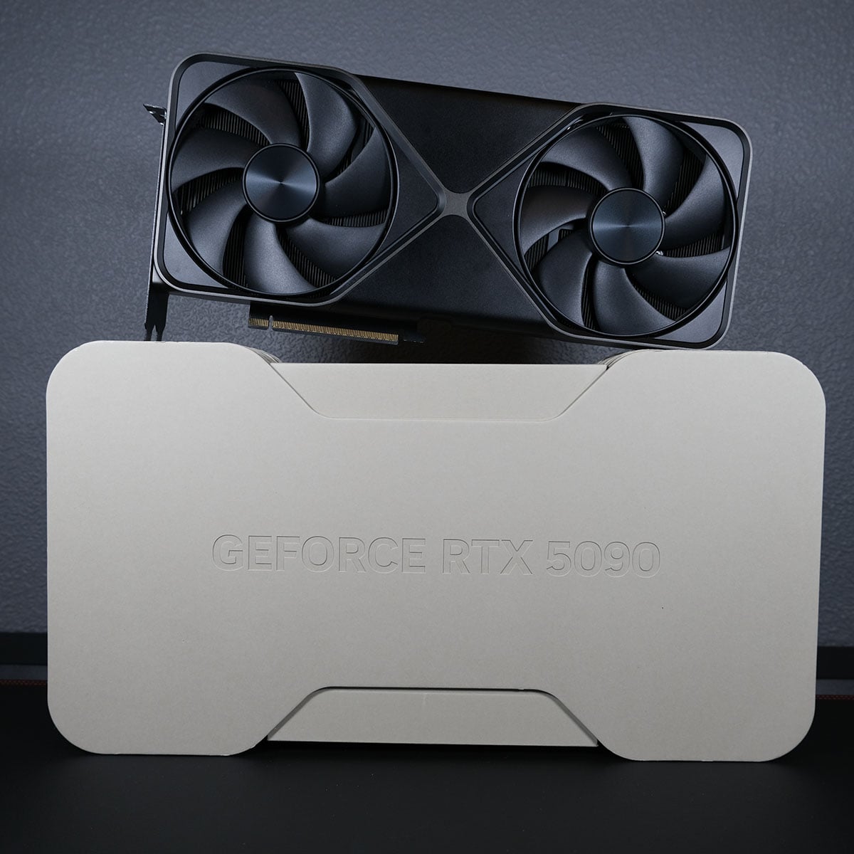 An Nvidia GeForce RTX 5090 Founders Edition, standing upright on top of its retail packaging.