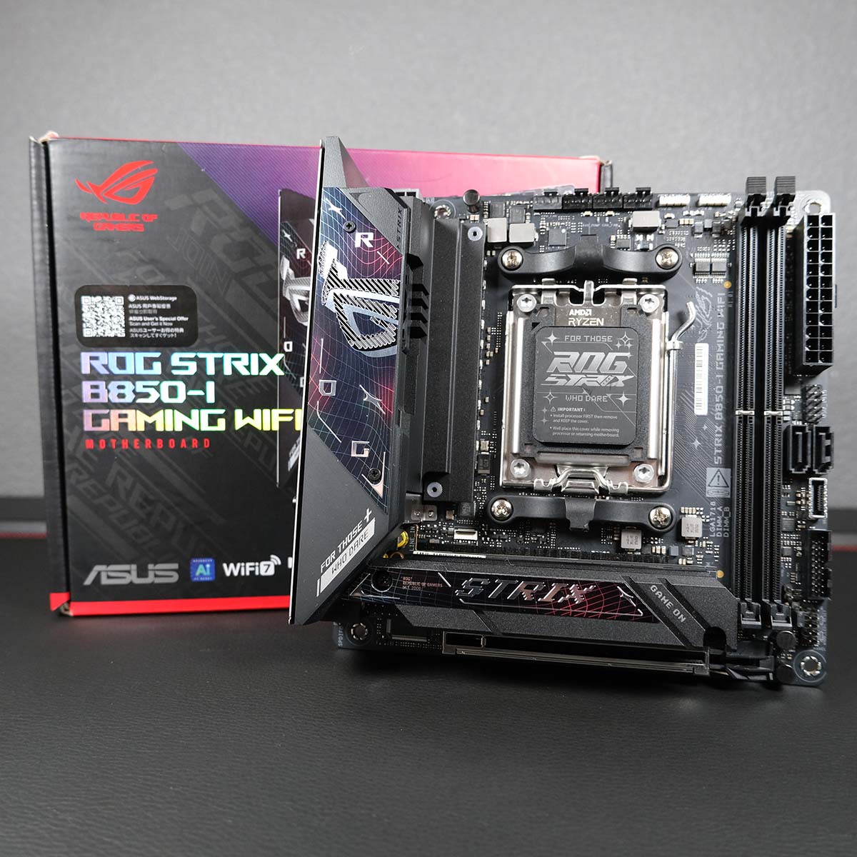 An Asus ROG Strix B850-I Gaming WiFi motherboard, standing upright against its retail packaging.