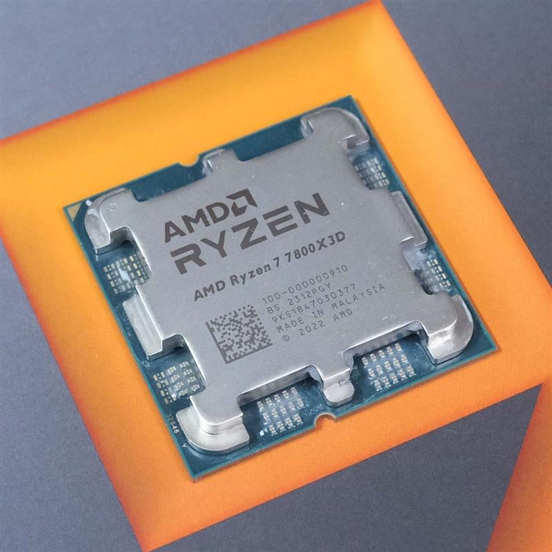 An AMD Ryzen 7 7800X3D laying on top of its retail packaging, surrounded by an orange square.
