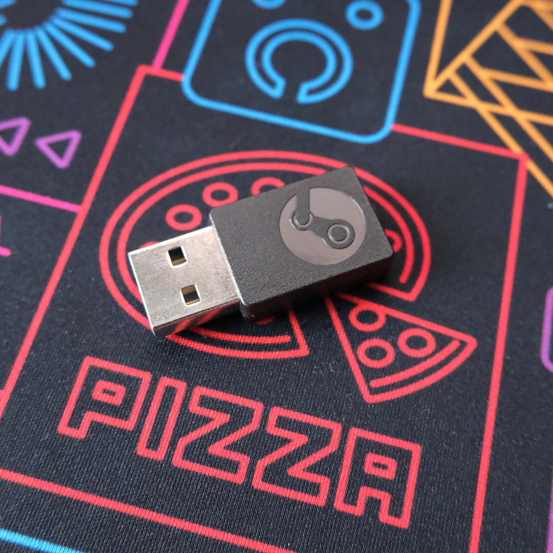 A Steam Controller USB-A dongle, lying atop a desk mat.