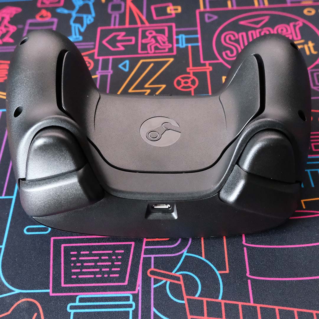 A Steam Controller, lying on its front, atop a desk mat.