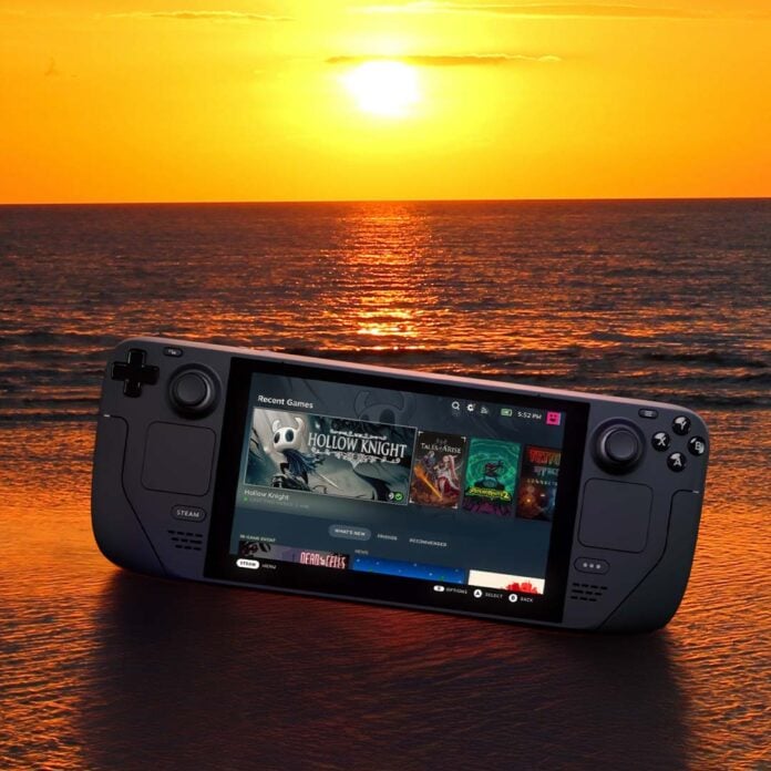 A Steam Deck LCD, lying on a beach with the sun setting behind it.
