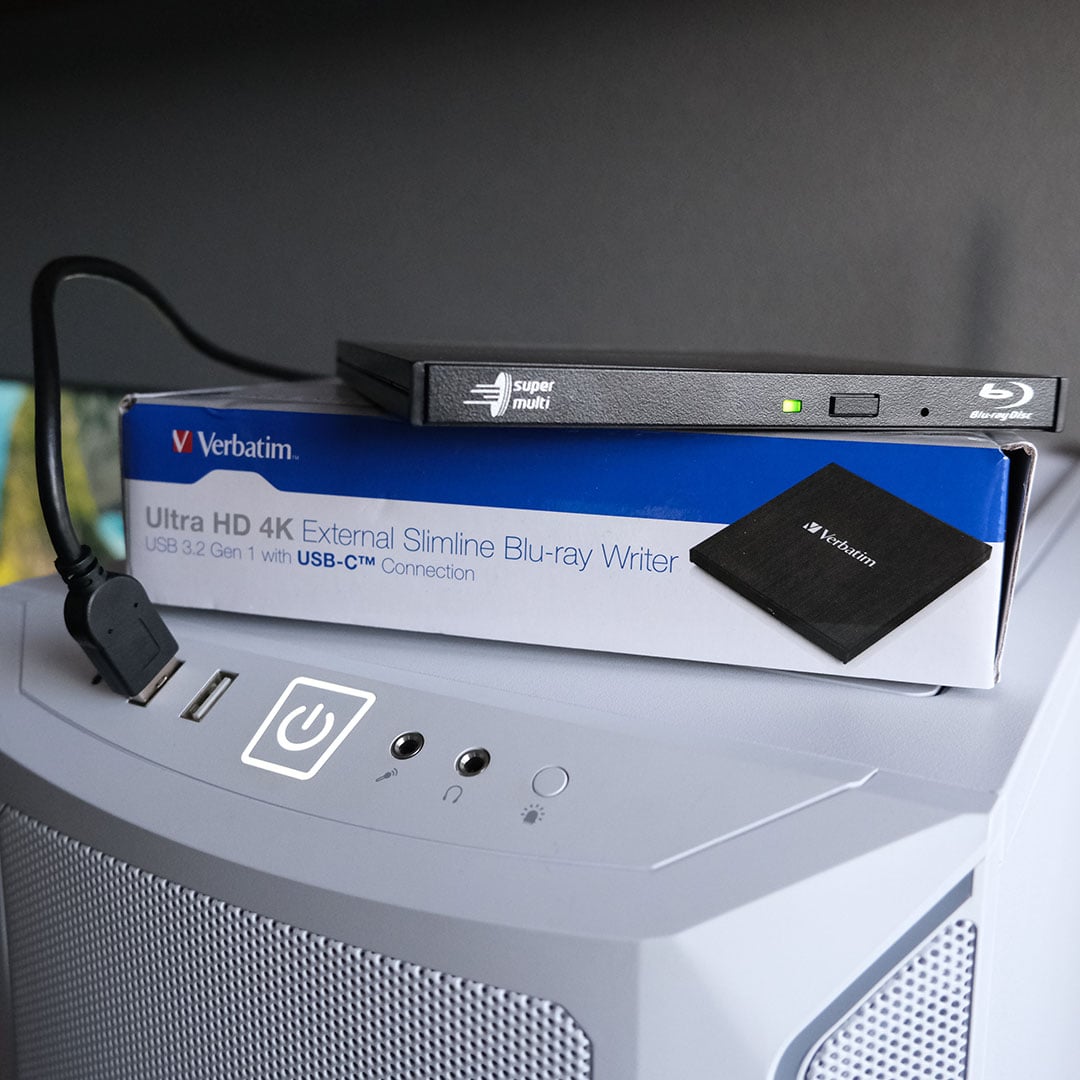 A 4K Blu-ray drive, atop its packaging, plugged into a PC.