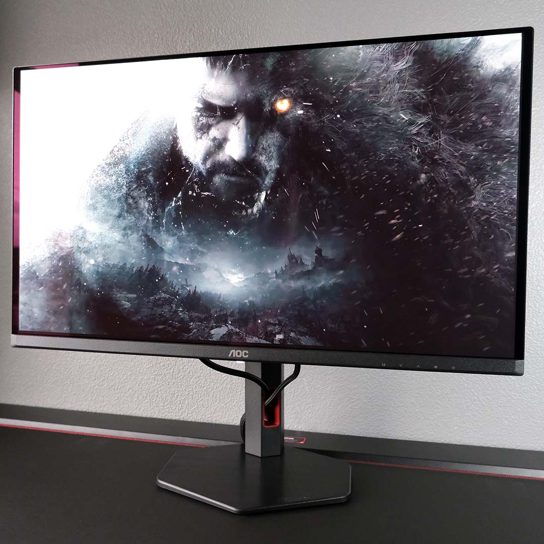 An AOC Q27G4SDR monitor displays key art from Resident Evil Village.