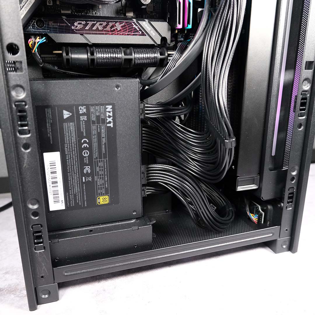 A close-up of cables at the bottom of the NZXT H2 Flow, with a complete system inside.