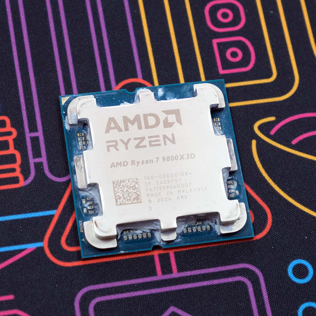 An AMD Ryzen 7 9800X3D sat atop a neon backdrop.
