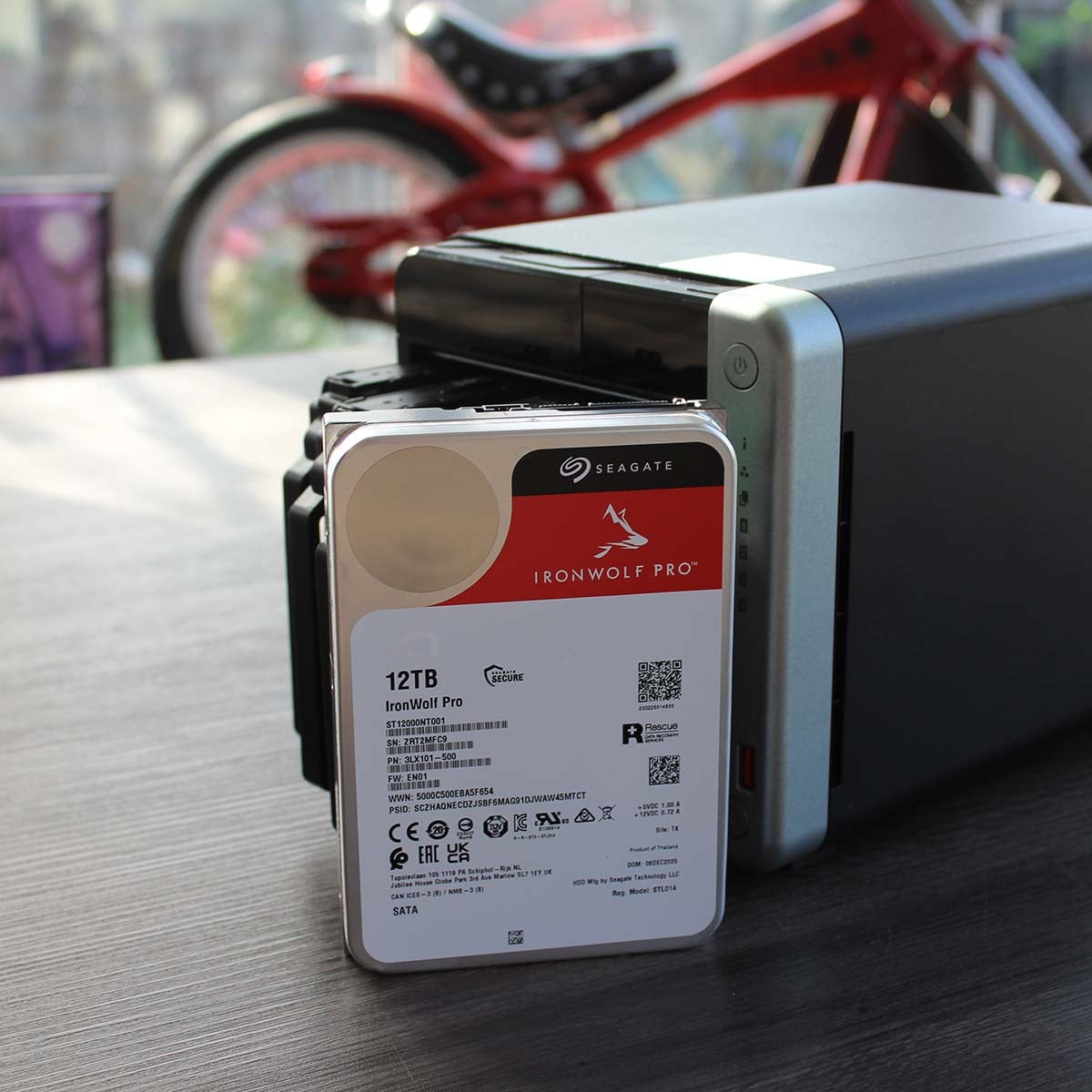 12TB Seagate IronWolf Pro hard drive next to a QNAP TS-x62A NAS