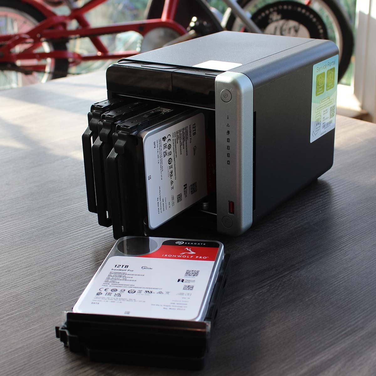 12TB Seagate IronWolf Pro hard drive next to a QNAP TS-x62A NAS