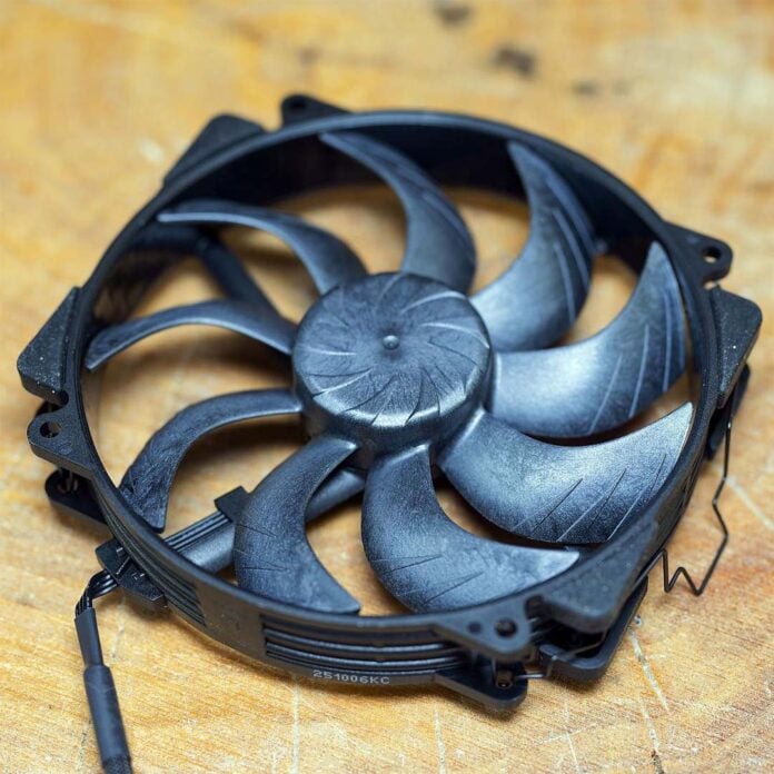 An NF-A14x25r G2 PWM chromax.black fan, resting atop a wooden surface.