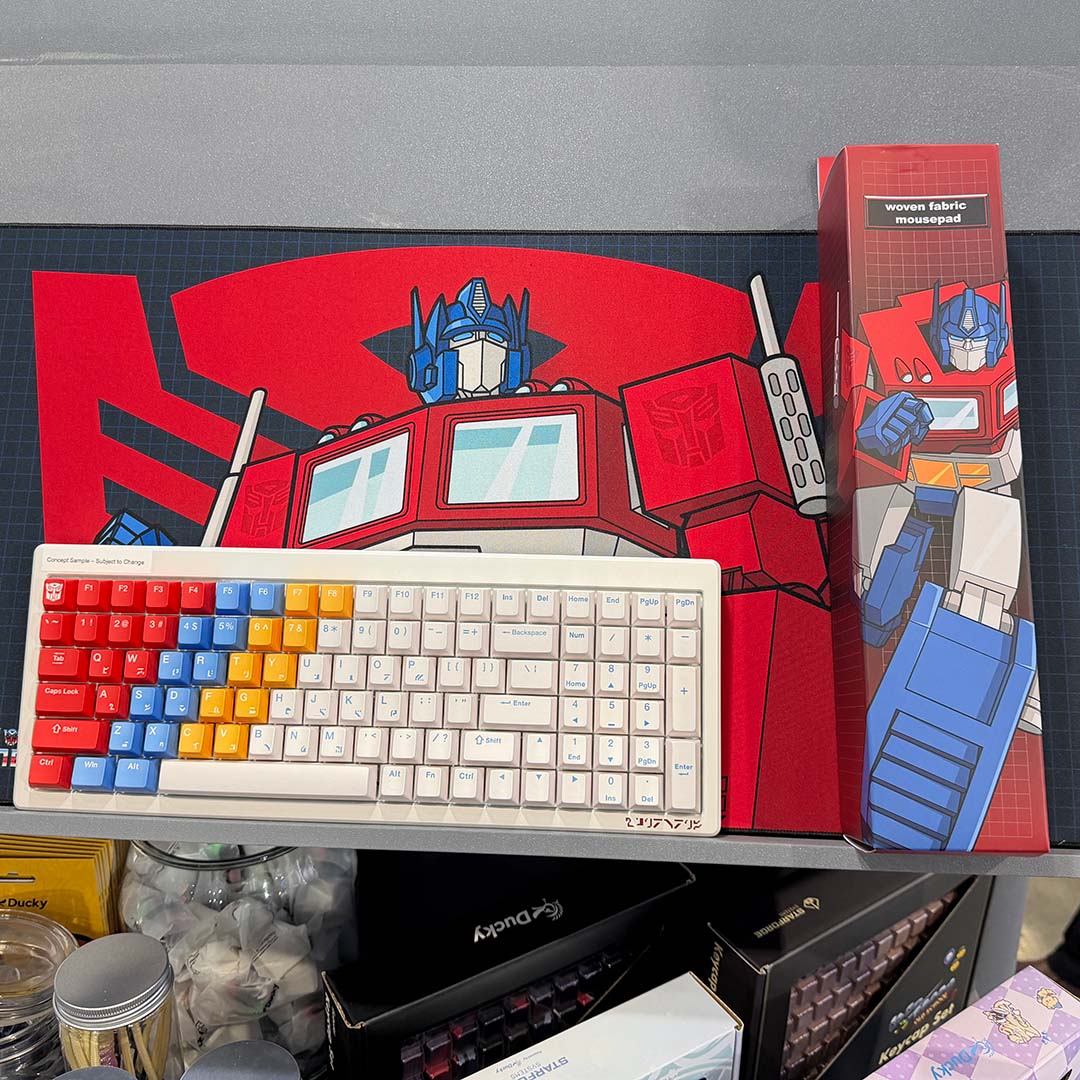 A top-down view of Ducky's Transformers keyboard concept, on top of a woven fabric mousepad complete with packaging.