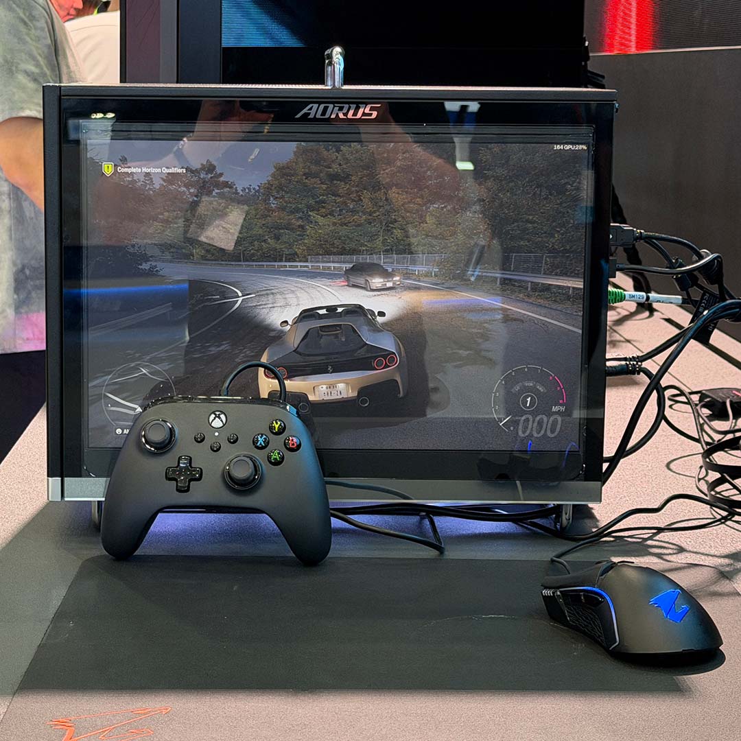 The Aorus C510 Glass Infinity, playing Forza Horizon on its display, with an Xbox controller in front of it.