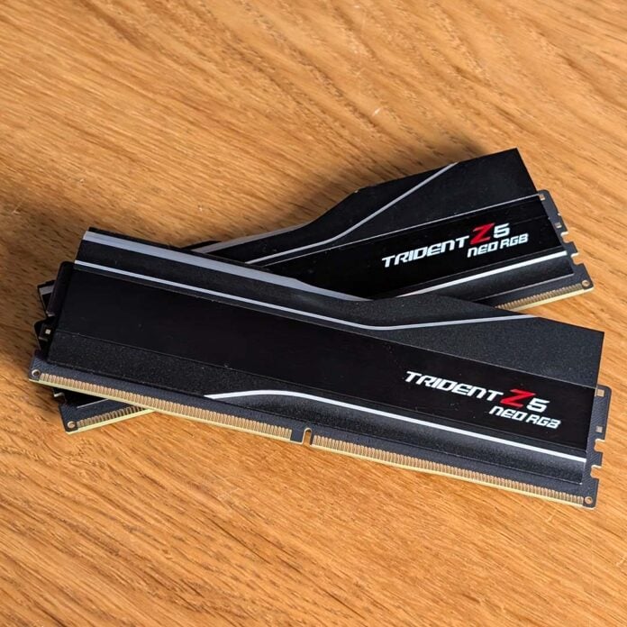 Two RAM sticks, sat atop one another, against a wooden surface.