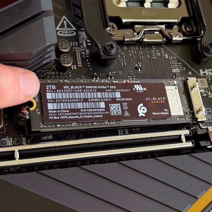 A thumb (left), hovering over a WD_Black SN8100 SSD.