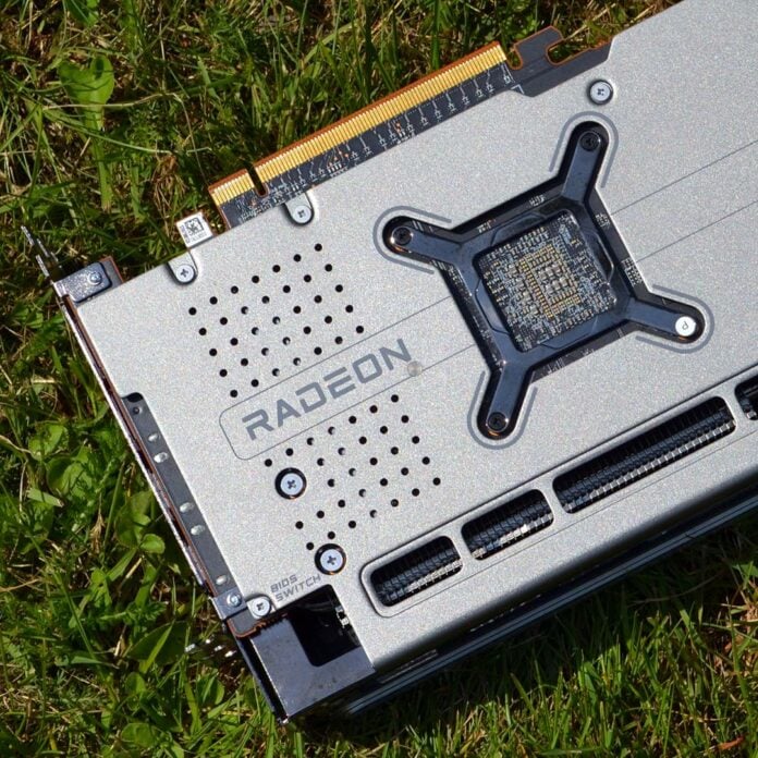 The backside of a Radeon RX 7000 series graphics card, lying on top of grass.