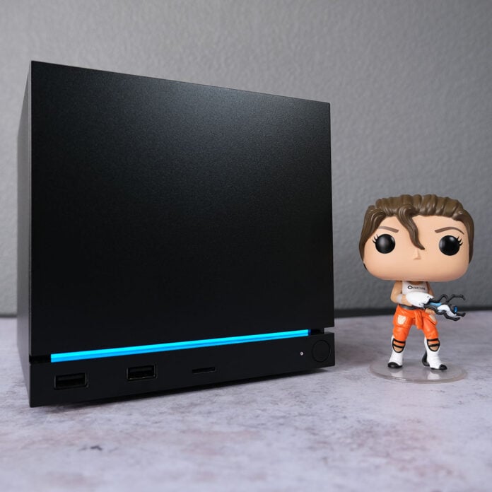 A Steam Machine (left) next to a Funko Pop Vinyl figure of Chell, the protagonist from Portal 2.