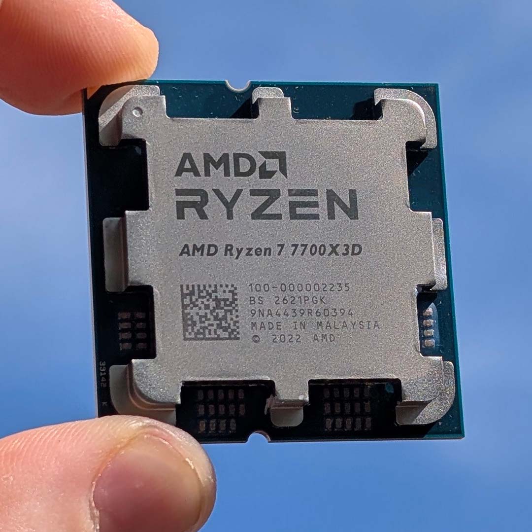 An AMD Ryzen 7 7700X3D against the sky, between two fingers.