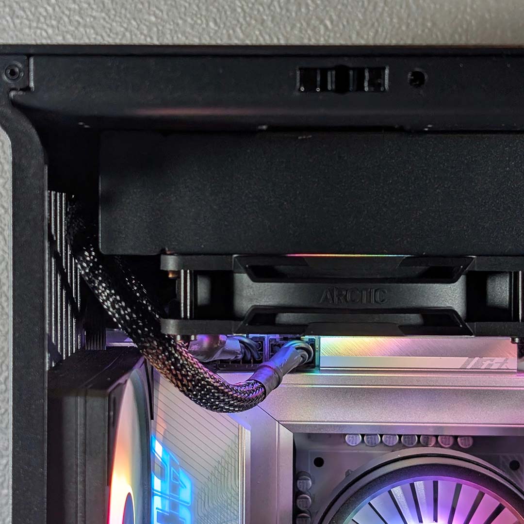 A close-up of CPU power cables routing along the side of a cooler inside the Hyte Y50 RGB.