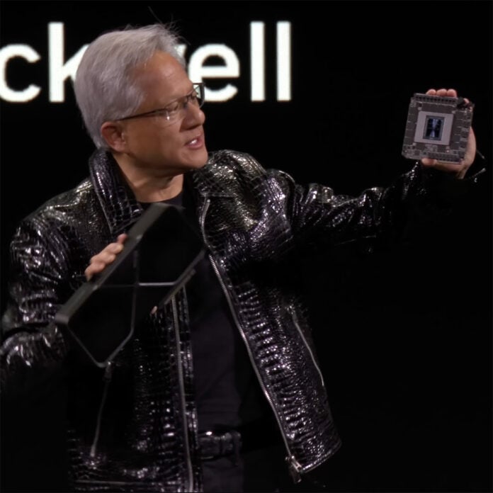 Nvidia CEO Jensen Huang holds a GeForce RTX 5090 Founders Edition in his right hand, while holding a GB202 GPU with 32GB of GDDR7 VRAM in his right.