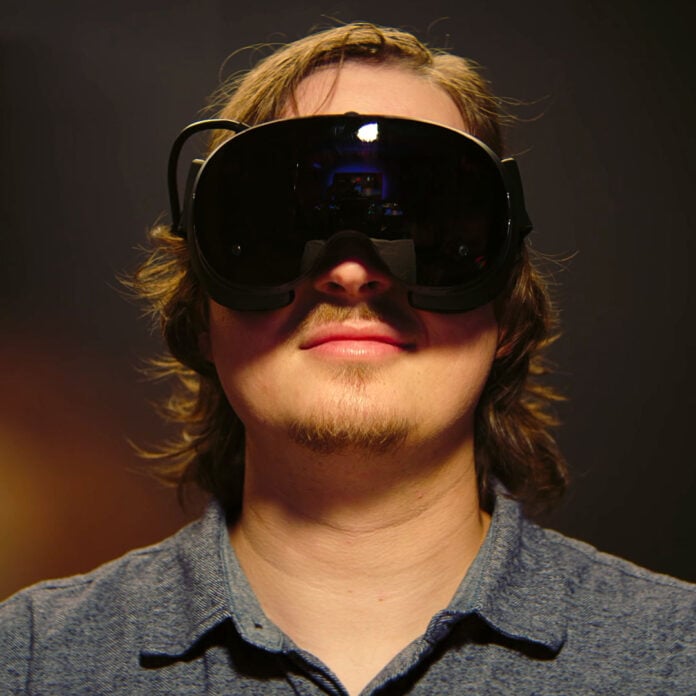 A male-presenting person wears a Steam Frame on their face.