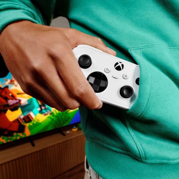 A hand holding a partially emerged Xbox Nano Controller from a hoodie pocket.
